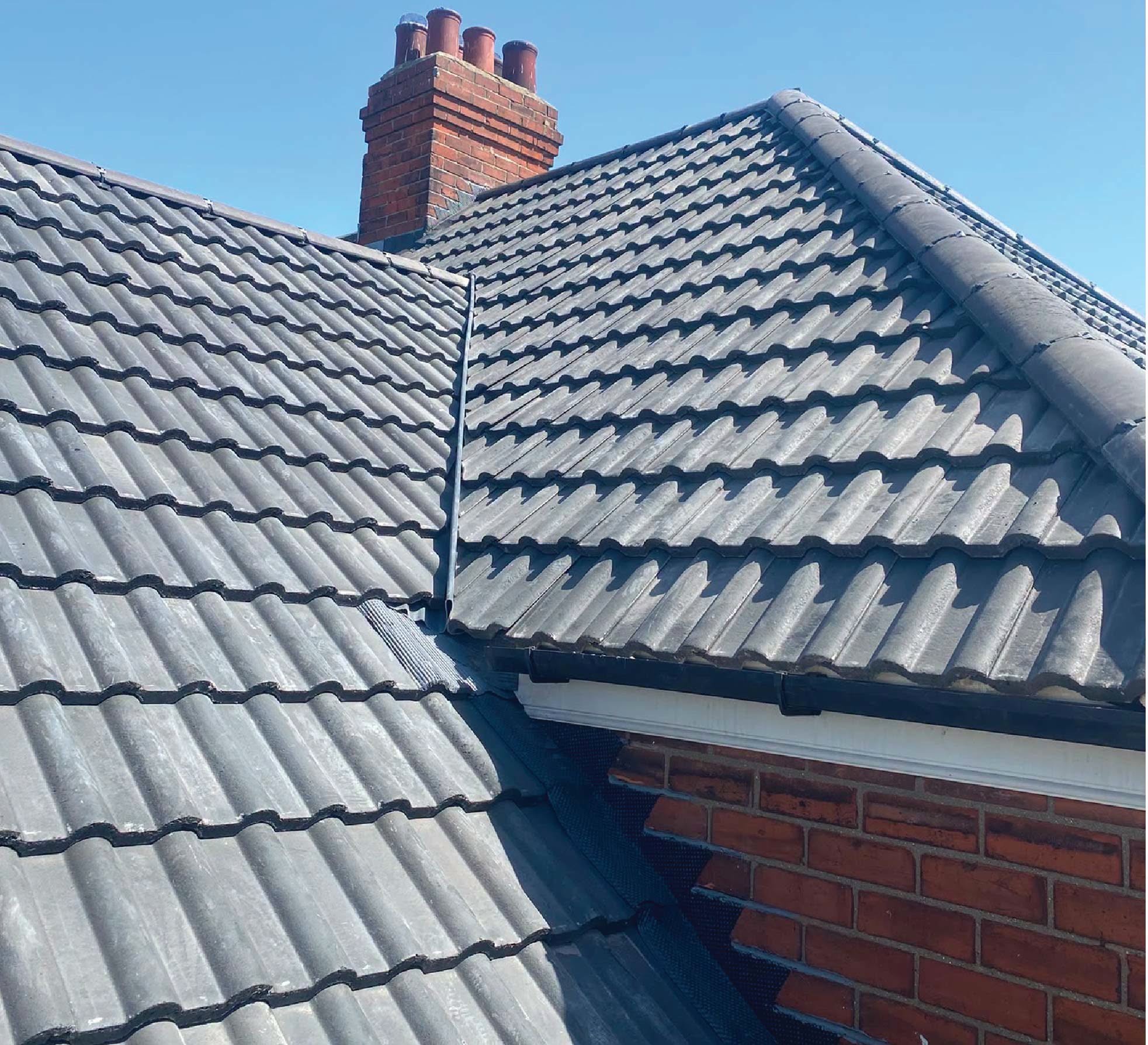 Re-roofed grey tile roof with brick chimney stacks